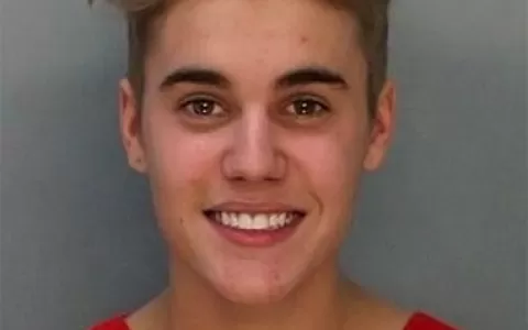 De uniforme, Justin Bieber posa sorridente para po